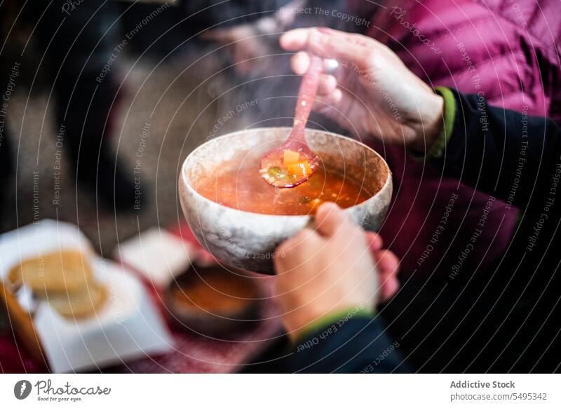 Unbekannter Mann in schwarzem Pullover hält dampfende Suppe mit Löffel in den Händen Person Schalen & Schüsseln Tisch Lebensmittel Speise Gemüse essen männlich