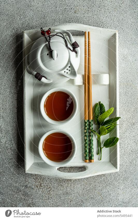 Teeservice im asiatischen Stil mit Zitronenblättern und Essstäbchen auf Tablett als Dekoration Kulisse Blatt Dekoration & Verzierung Tisch Oberfläche grau Tasse