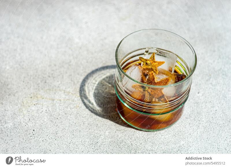 Glas Whiskey mit Eis und Orangenschalen auf grauer Oberfläche orange sich[Akk] schälen Form Stern Container durchsichtig hoher Winkel von oben Unschärfe