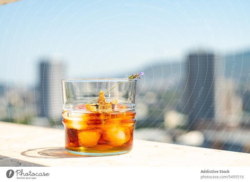 Glas Whiskey mit Eis und Orangenschalen auf weißer Oberfläche gegen unscharfe Stadt orange sich[Akk] schälen Form Stern Container durchsichtig Unschärfe