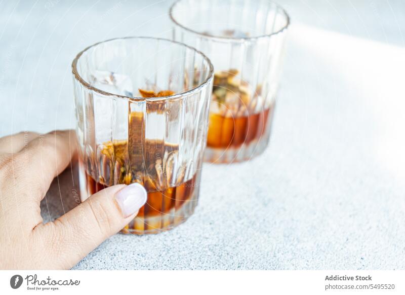 Anonyme Person mit Gläsern Whiskey mit Eis und Orangenschalen Glas orange sich[Akk] schälen Container durchsichtig Ernte Unschärfe verschwommener Hintergrund