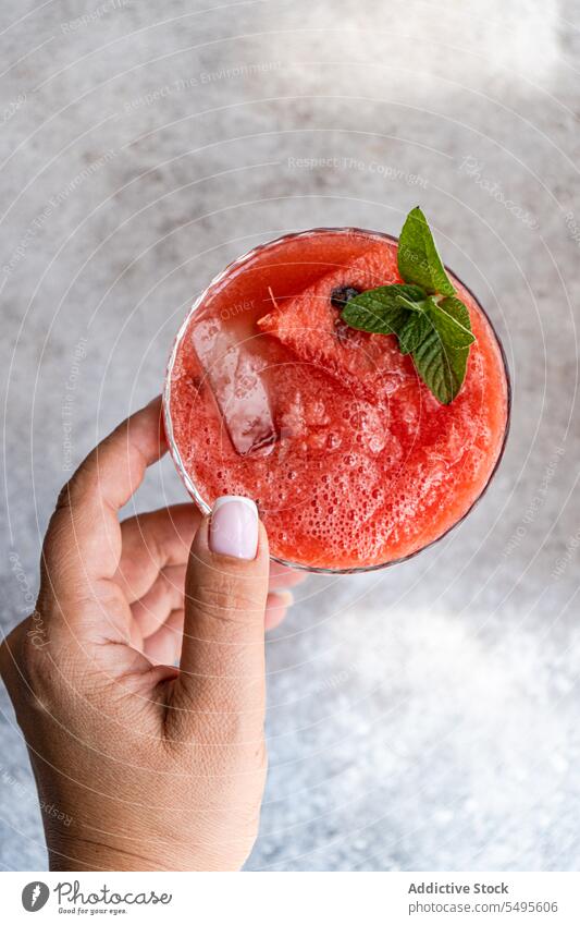 Crop-Person mit Margarita-Cocktail Smoothie Wassermelone Minze Hand frisch trinken Erfrischung Getränk Glas geschmackvoll Eiswürfel organisch mischen lecker