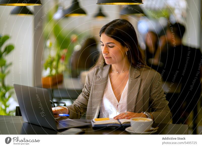 Konzentrierte Frau arbeitet am Laptop mit Kaffee in einem Cafe freiberuflich abgelegen Arbeit Café Projekt Konzentration Planer Notebook Job jung Gerät