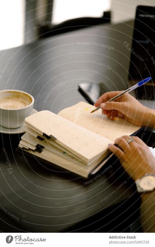 Unbekannte junge Frau sitzt am Tisch und macht Notizen in einem Café zur Kenntnis nehmen schreiben Notebook Notizblock Planer Schreibstift positiv Freizeit