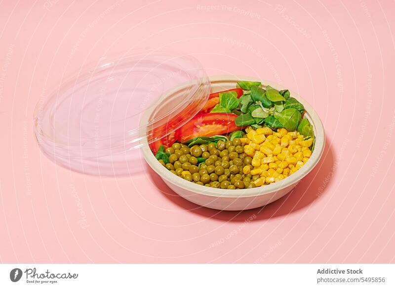 Salatschüssel auf rosa Hintergrund mit Plastikdeckel Schalen & Schüsseln Salatbeilage Lebensmittel Scheibe Tomate Spinat Blatt Mais Kernel Erbse Kunststoff