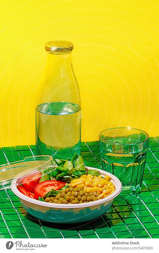 Salatschüssel auf grünem Hintergrund mit Plastikdeckel neben Flasche und Glas Wasser Schalen & Schüsseln Salatbeilage Lebensmittel Scheibe Tomate Spinat Blatt