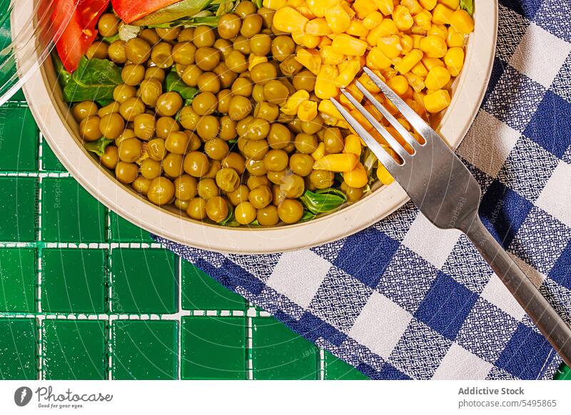 Salatschüssel auf Serviette auf grünem Hintergrund mit Plastikdeckel und Gabel Schalen & Schüsseln Salatbeilage Lebensmittel Scheibe Tomate Spinat Blatt Mais