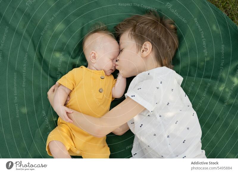 Niedlicher Bruder mit Baby-Geschwisterchen auf Decke im Park liegend Geschwisterkind Lügen Kuss Junge niedlich aussruhen Wochenende Zusammensein Kinder