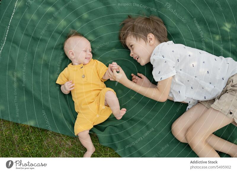 Niedlicher Bruder mit Baby-Geschwisterchen auf Decke im Park liegend Geschwisterkind Lügen Junge niedlich aussruhen Wochenende Zusammensein Lächeln Kinder