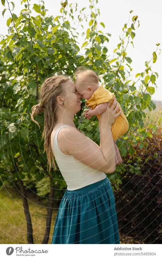Liebende Frau mit Baby im Park stehend Mutter tragen Sommer Wochenende Familie Säugling Zusammensein Mutterschaft Pflege Hipster Zuneigung Natur Glück eltern