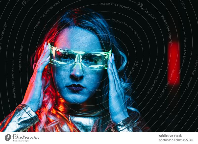 Kybernetisches junges Mädchen vor unscharfem Hintergrund kybernetisch lockig Behaarung blond Brille futuristisch anhaben hell reflektierend Bekleidung