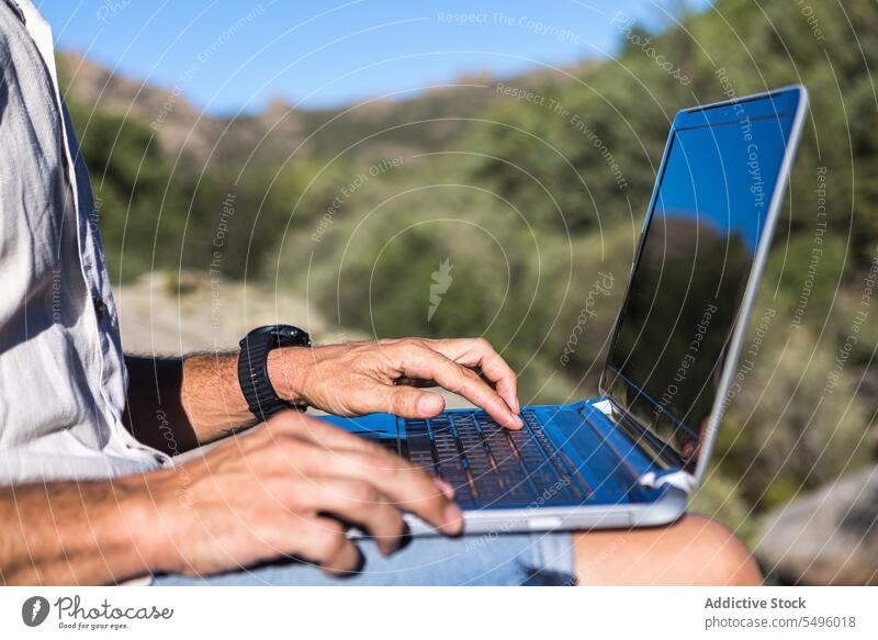 Anonymer Erntehelfer mit Laptop auf felsiger Klippe Mann freiberuflich Arbeit Natur Browsen Felsen benutzend Reisender männlich Pflanze abgelegen reisen