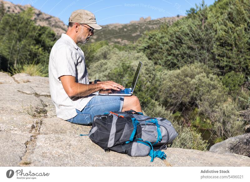 Mann mit Laptop auf felsiger Klippe freiberuflich Arbeit Natur Browsen Felsen benutzend Reisender männlich Pflanze abgelegen reisen Apparatur Sommer Gerät