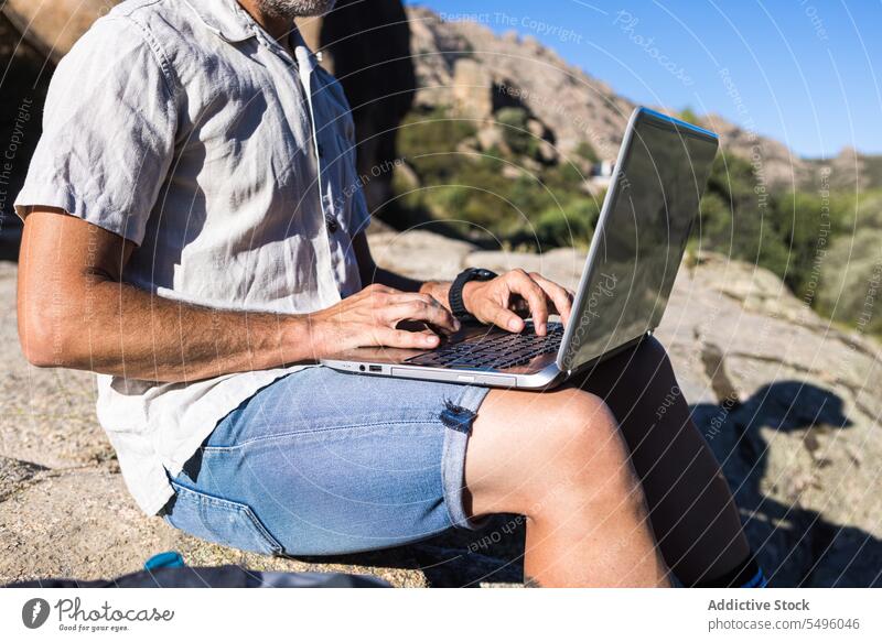Anonymer Erntehelfer mit Laptop auf felsiger Klippe Mann freiberuflich Arbeit Natur Browsen Felsen benutzend Reisender männlich Pflanze abgelegen reisen