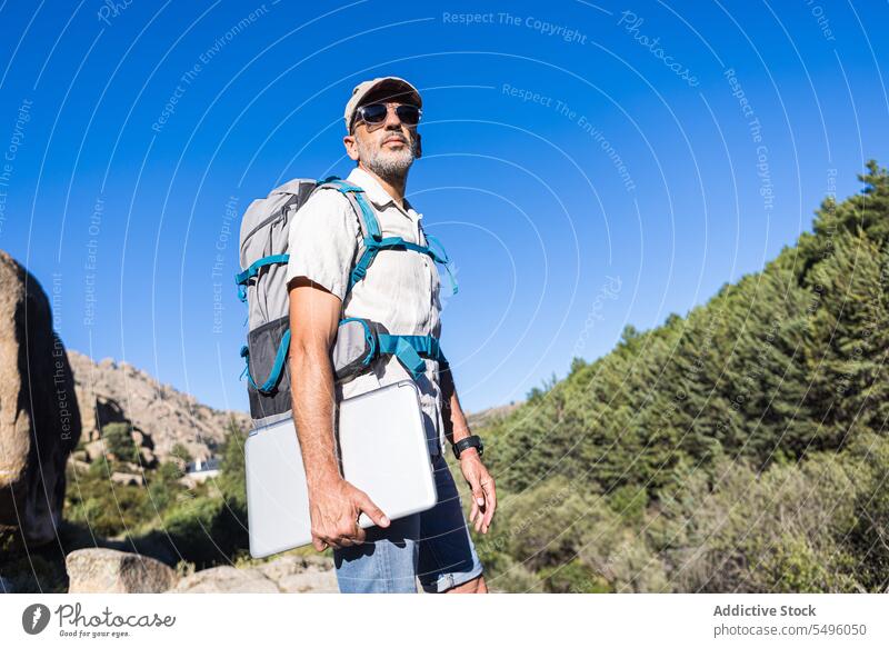Mann mit Laptop und Rucksack auf Klippe Wanderer Natur Wald Reisender Felsen Sommer männlich Abenteuer felsig reisen Wanderung grün Apparatur Gerät Umwelt