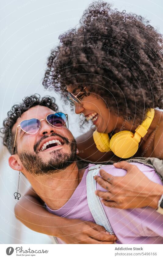 Fröhliches junges Paar kuschelt und sieht sich an Lachen Glück Umarmen genießen positiv Liebe heiter Kopfhörer Hipster Umarmung Sonnenbrille Zusammensein