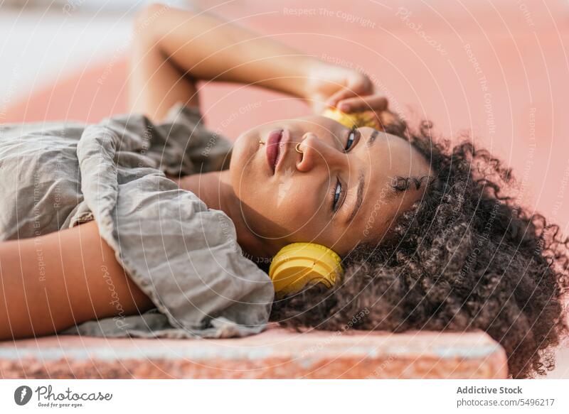 Auf dem Boden liegende Frau mit gelben Kopfhörern ruhen sich[Akk] entspannen Lächeln Lügen Glück Kälte allein positiv Windstille Inhalt Erholung modern froh