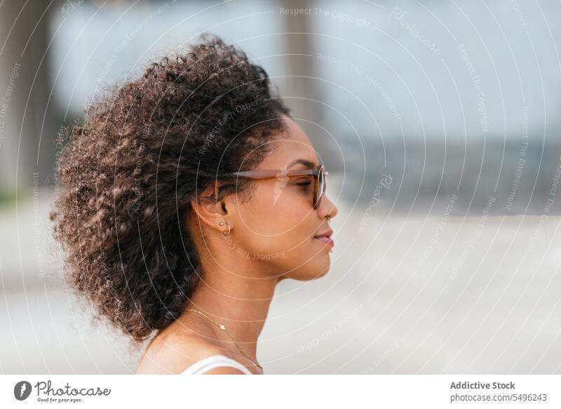 Junge Frau mit Lockenfrisur und Brille positiv Glück Sonnenbrille krause Haare genießen friedlich Windstille Accessoire Lifestyle Sommerzeit fliegendes Haar