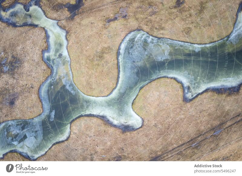Drohnenansicht eines sich schlängelnden gefrorenen Flusses auf sandigem Gelände bei Tageslicht Landschaft Natur Wald Wasser Umwelt rau malerisch spektakulär