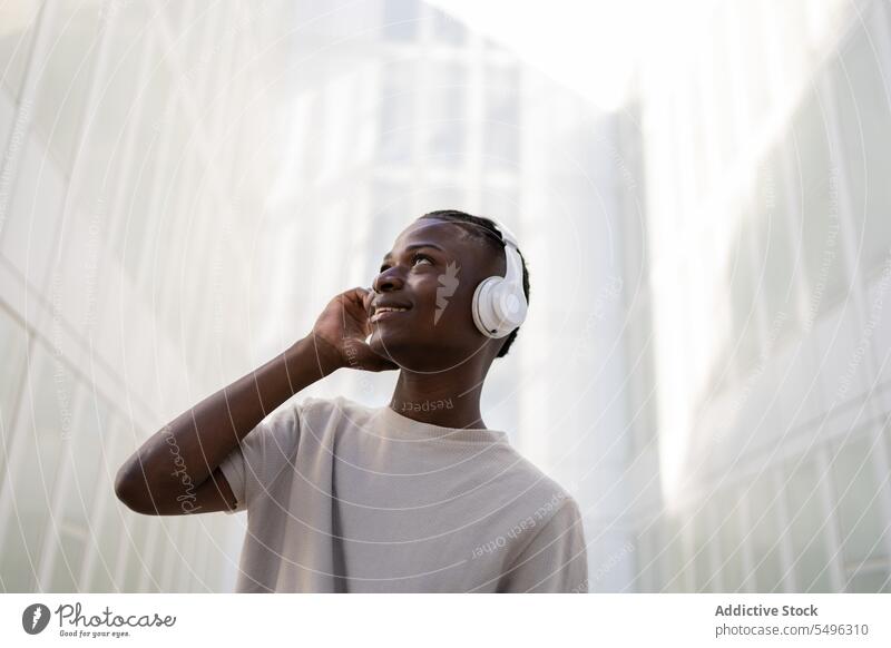 Schwarzer Mann mit Kopfhörern tanzt auf der Straße Teenager Musik Tanzen zuhören Drahtlos sich[Akk] bewegen Apparatur urban positiv jung ethnisch schwarz