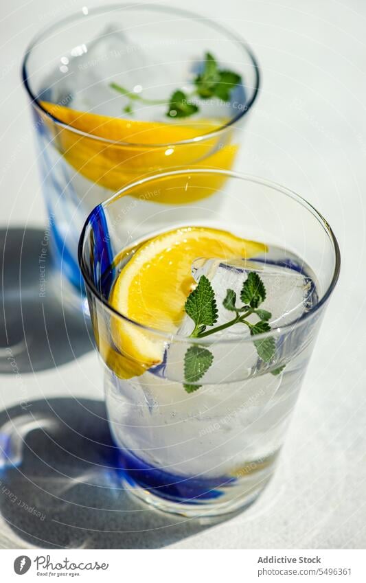 Sommercocktail mit Zitronenwodka, Zitronenscheibe und wilden Minzblättern Cocktail Vodka Scheibe Minze Blatt weiß Tisch Oberfläche Getränk Glas durchsichtig Eis