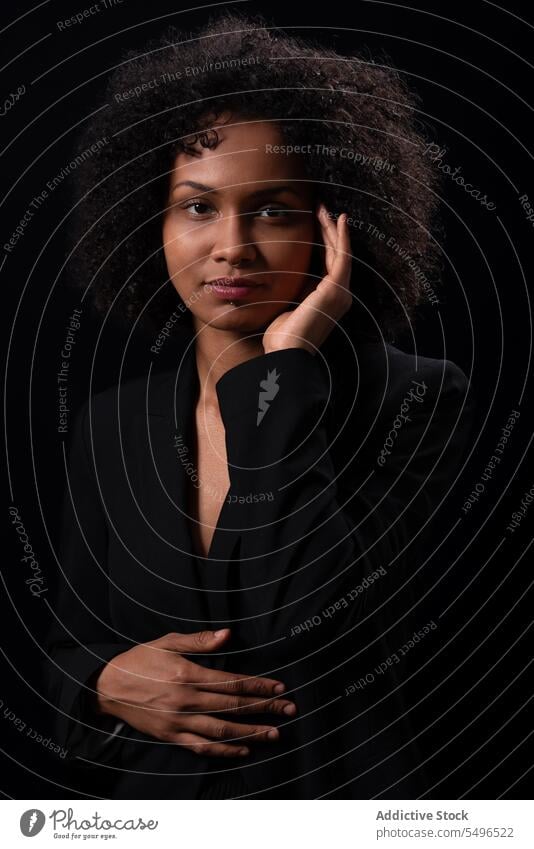 Ethnische Frau berührt ihr Gesicht und schaut in die Kamera Porträt krause Haare Vorschein Windstille Gesicht berühren Model Haare berühren selbstsicher