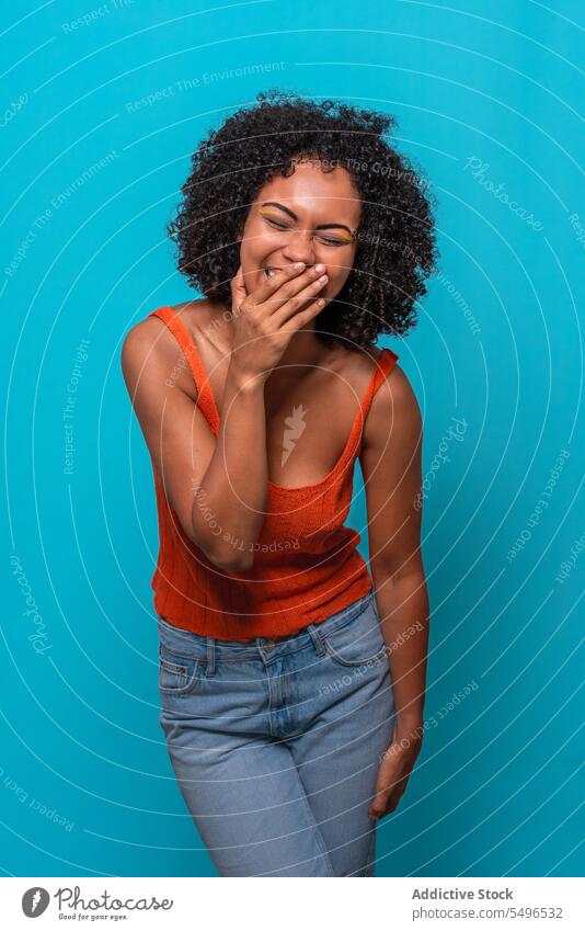 Fröhliche schwarze Frau mit lockigem Haar lächelt Model Afro-Look Frisur krause Haare heiter aufgeregt Lächeln Lachen Witz Afroamerikaner Humor Spaß haben