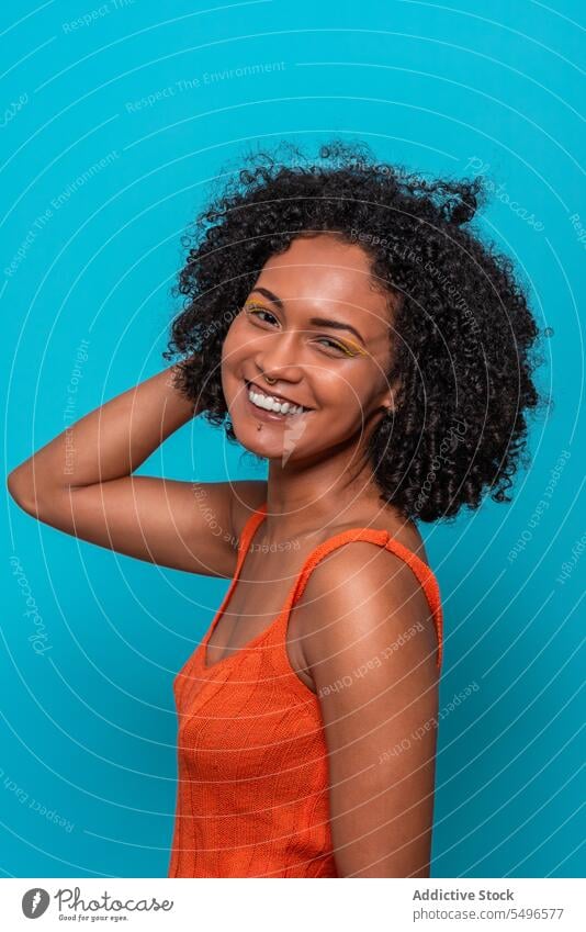 Lächelnde schwarze Frau in orangefarbenem Top schaut in die Kamera Mode Model schlank schlanke dunkles Haar krause Haare Afroamerikaner Outfit Stoff anhaben