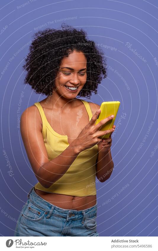 Glückliche ethnische Frau mit Mobiltelefon benutzend Smartphone online Lächeln heiter Browsen Afro-Look Apparatur Gerät krause Haare Internet Mobile Telefon