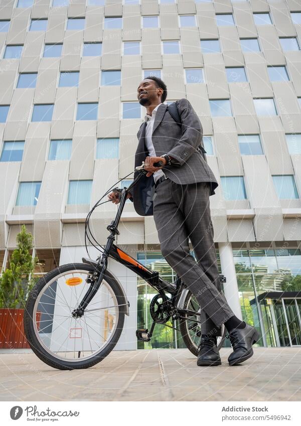 Ethnischer Unternehmer mit Fahrrad vor modernem Gebäude Geschäftsmann Mitarbeiter formal elegant Exekutive Arbeitsweg Verkehr Mann männlich ethnisch