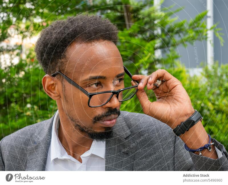 Afroamerikanischer Mann mit Brille schaut auf der Straße weg formal elegant achtsam Exekutive nachdenken Vorschein männlich ethnisch schwarz Afroamerikaner Typ