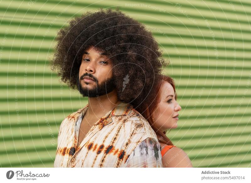 Ein gemischtrassiges Paar steht Rücken an Rücken auf grünem Hintergrund Seelenverwandter Partnerschaft Zuneigung Bonden Freundin Porträt Model Atelier Afro-Look