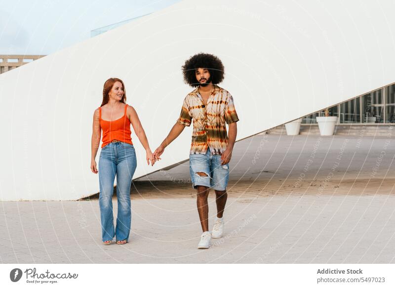 Multiethnisches Paar hält sich beim Gehen an den Händen Spaziergang Händchenhalten Liebe Zusammensein Bonden romantisch Partnerschaft Termin & Datum amourös
