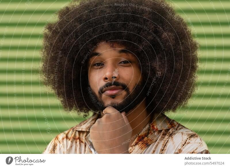 Selbstbewusster schwarzer Mann in trendiger Kleidung an der Wand Porträt Afro-Look Frisur Stil krause Haare ernst Windstille trendy Individualität Vorschein