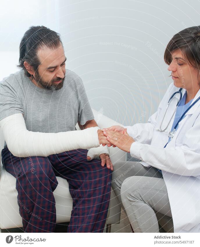Frau trägt ein Antiseptikum auf die verletzte Hand eines Mannes auf Krankenpfleger geduldig Wunde antiseptisch Antibiotikum bandagieren Verletzung gebrochen