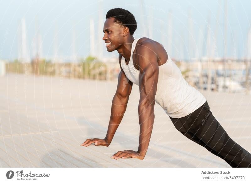 Schwarzer Mann macht Liegestütze an einer Böschung hochschieben Stauanlage MEER Training Übung Sport Sportbekleidung Wasser männlich Afroamerikaner Gesundheit