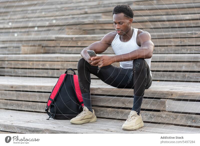 Schwarzer Sportler auf Treppe mit Smartphone Athlet Sportbekleidung Mobile Browsen Internet Schritt Kälte männlich schwarz Afroamerikaner Model passen muskulös