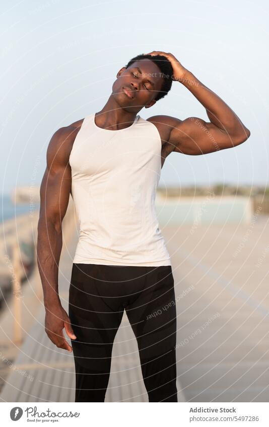 Schwarzer Mann berührt Kopf an Böschung Windstille Tastkopf ernst Sportler Stauanlage Sportbekleidung Augen geschlossen ruhig besinnlich männlich nachdenklich