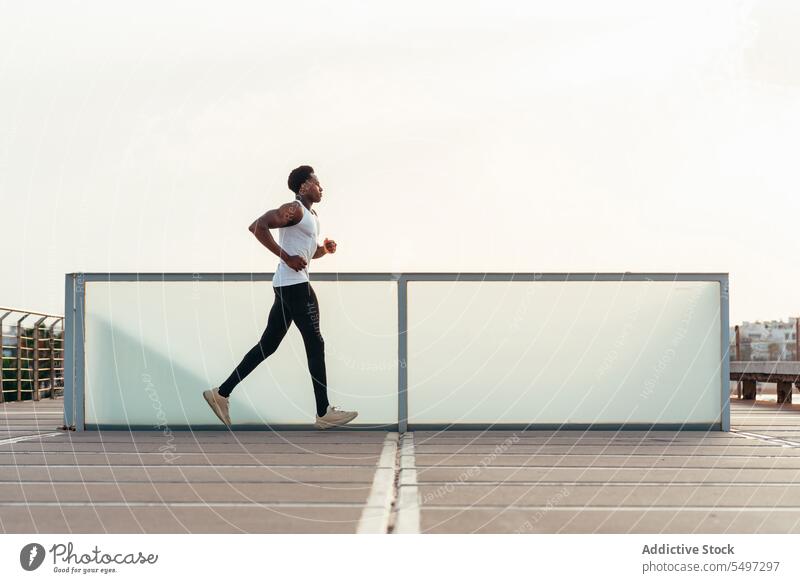 Schwarzer Sportler läuft auf Sportplatz Athlet joggen laufen Sportbekleidung Sportpark Aufwärmen Pier hölzern Übung männlich schwarz Afroamerikaner Model Herz