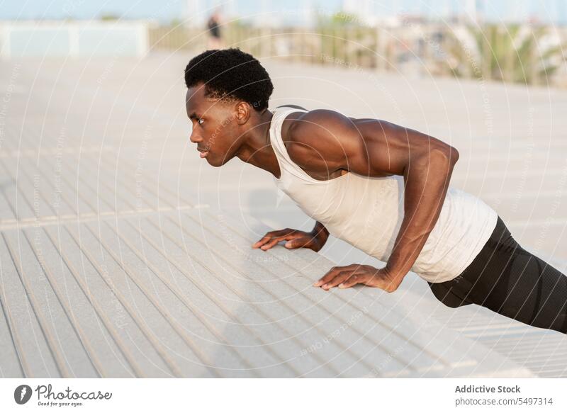 Schwarzer Mann macht Liegestütze an einer Böschung hochschieben Stauanlage MEER Training Übung Sport Porträt Sportbekleidung Wasser männlich Afroamerikaner