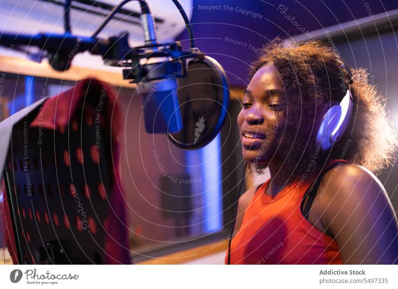 Schwarze Frau singt und kreiert ein Lied Sängerin singen Aufzeichnen kreieren hohe Note Mikrofon Kopfhörer Musik Atelier schwarz Afroamerikaner professionell