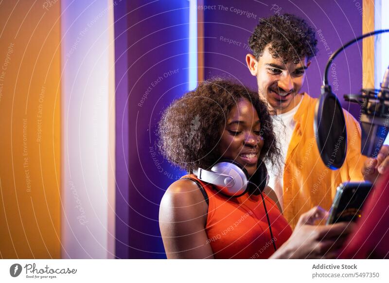 Ein Mann und eine schwarze Frau hören ein Lied auf ihrem Smartphone Sängerin zuhören Aufzeichnen schreiben Musik Gesang Atelier Ergebnis Glück Afroamerikaner
