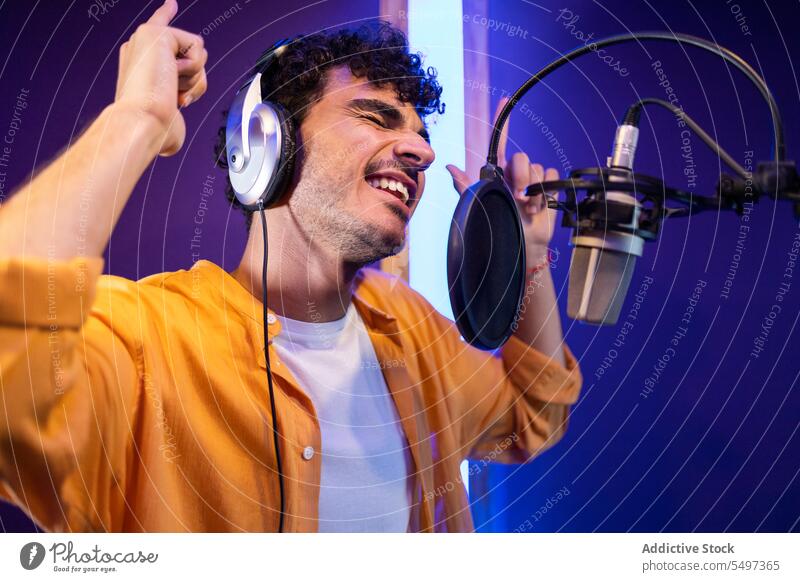 Mann singt und nimmt ein Lied auf Sänger Aufzeichnen Musik singen hohe Note Mikrofon Atelier nach oben zeigen zur Kenntnis nehmen männlich professionell