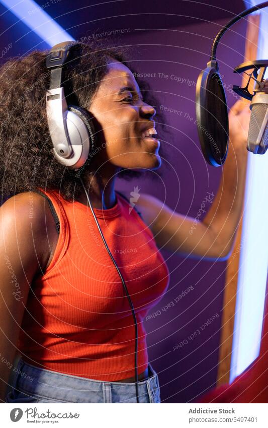 Schwarze Frau singt und kreiert ein Lied Sängerin singen Aufzeichnen kreieren hohe Note Mikrofon Kopfhörer Musik Atelier schwarz Afroamerikaner professionell