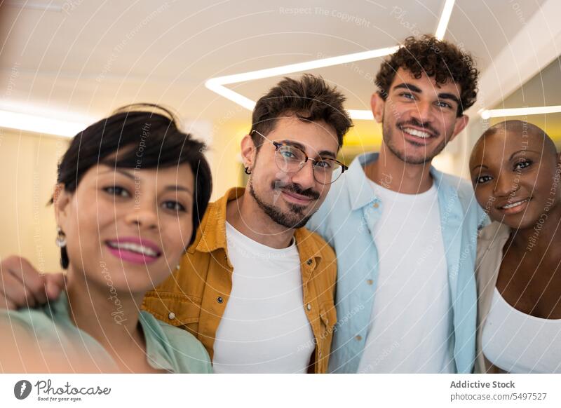 Fröhliche multiethnische Freunde stehen im Büro und machen zusammen ein Selfie Menschengruppe Kollege Team Smartphone Zusammensein Lächeln positiv heiter