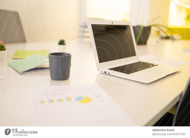 Laptop auf dem Schreibtisch in einem modernen Büro Arbeitsplatz Tasse Arbeitsbereich Kaffee Netbook Heißgetränk Gerät Apparatur Getränk Tisch Papier trinken