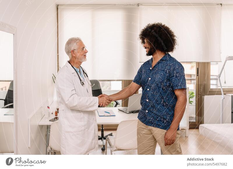 Lächelnder Arzt und Patient beim Händeschütteln Männer geduldig Hände schütteln Krankenhaus Gesundheitswesen Klinik heiter Gruß männlich medizinisch älter