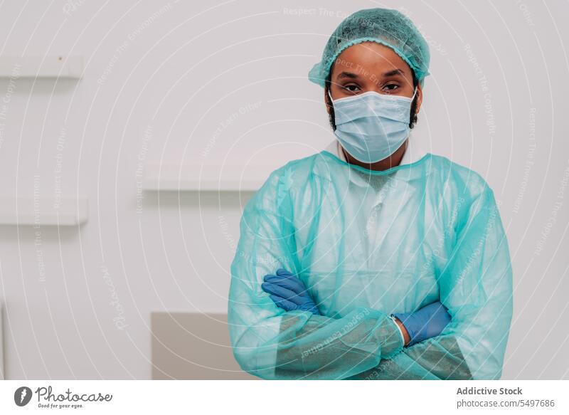 Ethnischer männlicher Chirurg mit verschränkten Armen schaut in die Kamera im Krankenhaus Mann Arzt die Arme verschränkt professionell Spezialist ernst Klinik