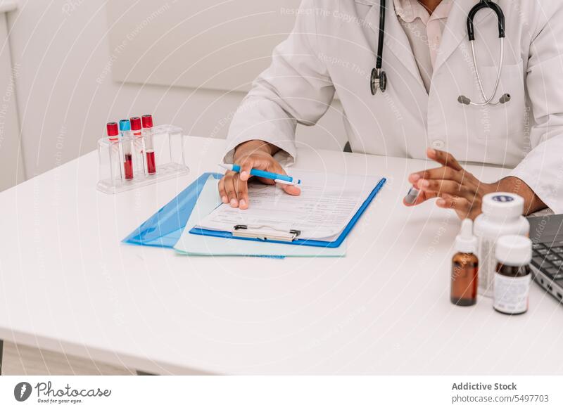 Fokussierter Arzt mit Blutteströhrchen, der nach dem Bluttest Informationen in ein Formular schreibt Mann Prüfung Arbeit schreiben Tube Notizen Reagenzglas