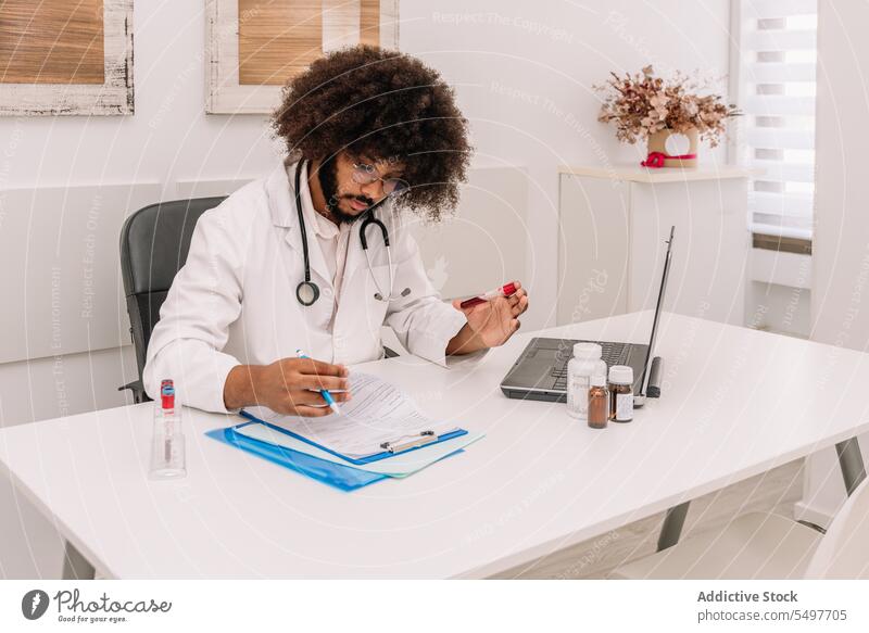 Fokussierter Arzt mit Blutteströhrchen, der nach dem Bluttest Informationen in ein Formular schreibt Mann Prüfung Arbeit schreiben Tube Reagenzglas